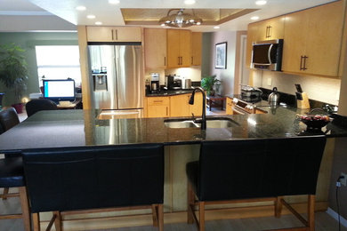 Mid-sized elegant u-shaped kitchen pantry photo in Tampa with an undermount sink, flat-panel cabinets, light wood cabinets, granite countertops, beige backsplash, stainless steel appliances and a peninsula