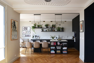 Idées déco pour une grande cuisine ouverte contemporaine en L avec un évier encastré, un placard à porte affleurante, des portes de placard noires, un plan de travail en quartz modifié, une crédence blanche, une crédence en quartz modifié, un électroménager en acier inoxydable, parquet clair, îlot et un plan de travail blanc.