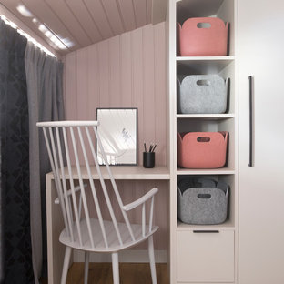 Design ideas for a small modern study in Lyon with pink walls, light hardwood flooring, a built-in desk and beige floors.