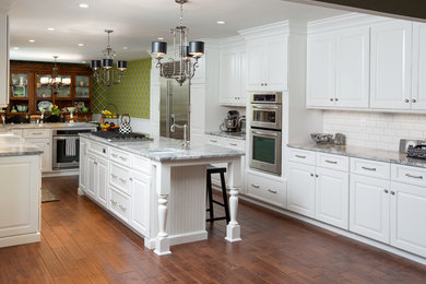 Inspiration for a large timeless u-shaped medium tone wood floor eat-in kitchen remodel in Columbus with a farmhouse sink, white cabinets, granite countertops, white backsplash, stainless steel appliances and an island