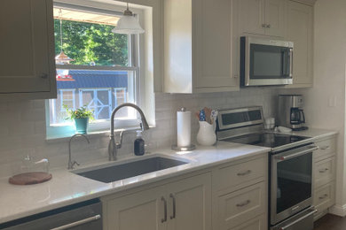 Example of a small classic galley medium tone wood floor eat-in kitchen design in Other with an undermount sink, beige cabinets, quartz countertops, white backsplash, ceramic backsplash, stainless steel appliances, no island and white countertops