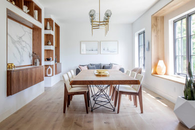 This is an example of a midcentury separate dining room in Vancouver with white walls, light hardwood floors and beige floor.