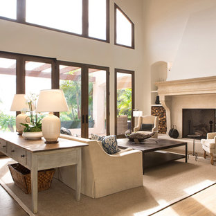 Modelo de salón para visitas abierto, mediterráneo, de tamaño medio, sin televisor, con paredes beige, suelo de madera en tonos medios, chimenea tradicional y marco de chimenea de yeso