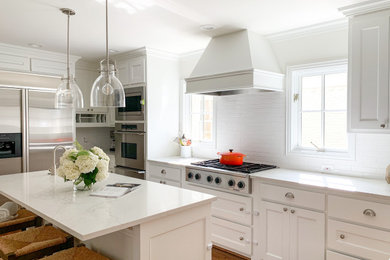 Kitchen - transitional dark wood floor and brown floor kitchen idea in Dallas with a farmhouse sink, white cabinets, quartzite countertops, white backsplash, ceramic backsplash, stainless steel appliances, an island and white countertops