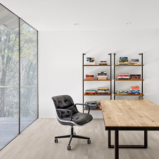 Photo of a modern home office and library in Austin with white walls, light hardwood flooring, a freestanding desk and beige floors.