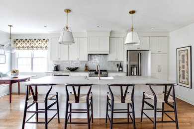 Transitional l-shaped medium tone wood floor and brown floor eat-in kitchen photo in Richmond with a farmhouse sink, shaker cabinets, white cabinets, gray backsplash, stainless steel appliances, an island and gray countertops