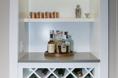 Mid-sized country dark wood floor home bar photo in Kansas City with an undermount sink, shaker cabinets, white cabinets, solid surface countertops, white backsplash and subway tile backsplash