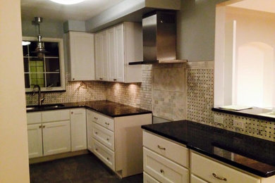 Eat-in kitchen - traditional l-shaped eat-in kitchen idea in Detroit with a drop-in sink, raised-panel cabinets, white cabinets, stone slab backsplash and stainless steel appliances