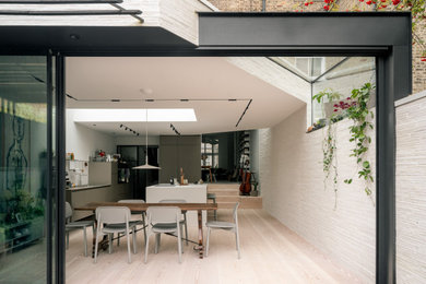 Design ideas for a contemporary open plan dining room in London with white walls, brick walls and a feature wall.