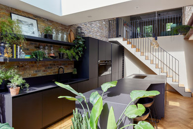 Large contemporary single-wall eat-in kitchen in London with flat-panel cabinets, black cabinets, quartz benchtops and with island.