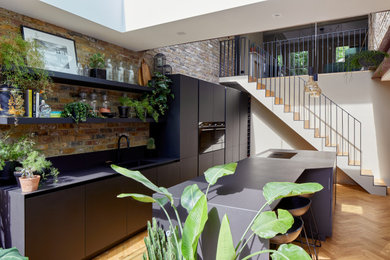 Large contemporary single-wall kitchen/diner in London with flat-panel cabinets, black cabinets, engineered stone countertops and an island.