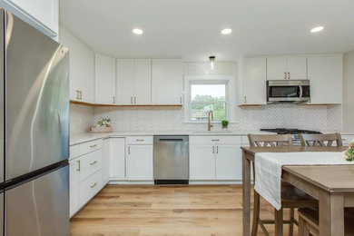 Mid-sized minimalist l-shaped laminate floor and brown floor eat-in kitchen photo in Boston with an undermount sink, shaker cabinets, white cabinets, quartzite countertops, white backsplash, subway tile backsplash, stainless steel appliances, no island and multicolored countertops