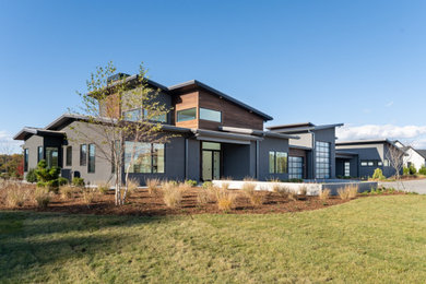 Imagen de fachada de casa gris y gris moderna grande de una planta con revestimientos combinados y tejado de varios materiales