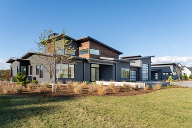 Large modern gray one-story mixed siding house exterior idea in Other with a mixed material roof and a gray roof