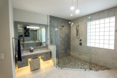 This is an example of a large contemporary master bathroom in Other with shaker cabinets, grey cabinets, a double shower, a two-piece toilet, white tile, porcelain tile, grey walls, porcelain floors, an undermount sink, quartzite benchtops, grey floor, a hinged shower door and grey benchtops.