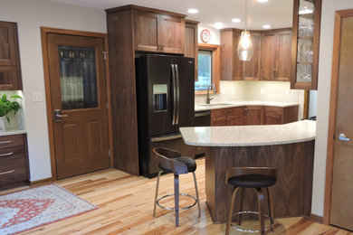 Inspiration for a craftsman galley light wood floor eat-in kitchen remodel in Other with an undermount sink, recessed-panel cabinets, dark wood cabinets, quartzite countertops, beige backsplash, ceramic backsplash, black appliances, a peninsula and beige countertops