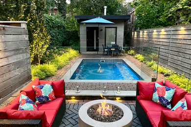 Photo of a mid-sized eclectic full sun backyard concrete paver and wood fence landscaping in Toronto with a fire pit.