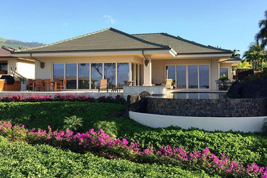 Large traditional one-storey beige house exterior in Hawaii with stone veneer, a hip roof and a shingle roof.