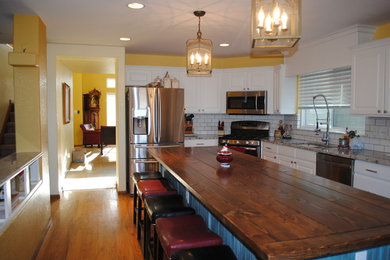 Eat-in kitchen - mid-sized country l-shaped medium tone wood floor eat-in kitchen idea in Denver with an undermount sink, raised-panel cabinets, white cabinets, granite countertops, white backsplash, subway tile backsplash, stainless steel appliances and an island
