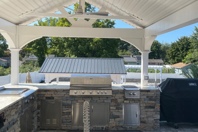 Large mountain style backyard concrete paver patio kitchen photo in Bridgeport with a gazebo