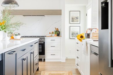 Open concept kitchen - mid-sized contemporary u-shaped vinyl floor and brown floor open concept kitchen idea in Vancouver with an undermount sink, shaker cabinets, white cabinets, quartzite countertops, multicolored backsplash, black appliances, an island and multicolored countertops