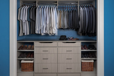 This is an example of a mid-sized contemporary men's built-in wardrobe in Orange County with flat-panel cabinets, light wood cabinets, carpet and beige floor.