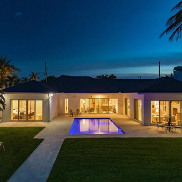 Evening Pool House With Ambient Lighting, Covered Seating Area, and Symmetrical