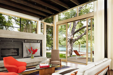 Inspiration for a large contemporary medium tone wood floor living room remodel in Austin with a standard fireplace and a concrete fireplace