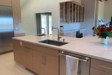 Photo of a contemporary eat-in kitchen in San Francisco with an undermount sink, flat-panel cabinets, light wood cabinets, quartz benchtops, stainless steel appliances, porcelain floors, multiple islands and white benchtop.
