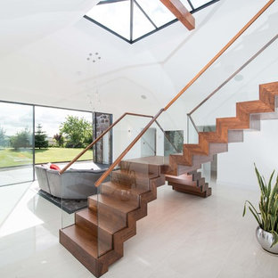 This is an example of a medium sized contemporary wood l-shaped glass railing staircase in Other with wood risers.