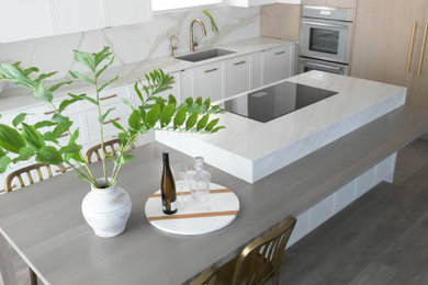Modern inredning av ett stort vit vitt kök, med en undermonterad diskho, släta luckor, skåp i ljust trä, bänkskiva i kvarts, vitt stänkskydd, rostfria vitvaror, vinylgolv och en köksö