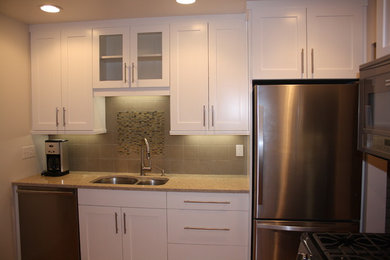 Enclosed kitchen - small contemporary l-shaped medium tone wood floor enclosed kitchen idea in New York with an undermount sink, white cabinets, quartzite countertops, ceramic backsplash, stainless steel appliances and no island