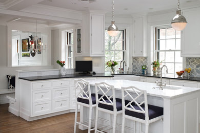 Inspiration for a mid-sized contemporary u-shaped open plan kitchen in Boston with a farmhouse sink, recessed-panel cabinets, white cabinets, granite benchtops, grey splashback, ceramic splashback, stainless steel appliances, medium hardwood floors, with island and brown floor.