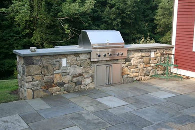 Large island style backyard stone patio kitchen photo in Denver with no cover