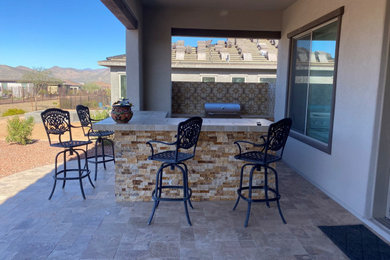 Inspiration for a large transitional backyard patio in Phoenix with an outdoor kitchen, natural stone pavers and a roof extension.