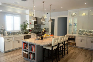 Enclosed kitchen - large transitional u-shaped porcelain tile enclosed kitchen idea in Miami with a farmhouse sink, shaker cabinets, white cabinets, quartzite countertops, multicolored backsplash, glass tile backsplash, stainless steel appliances and an island