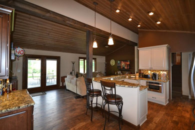 This is an example of a mid-sized country u-shaped eat-in kitchen in Milwaukee with white cabinets, granite benchtops, multi-coloured splashback, stainless steel appliances and vinyl floors.