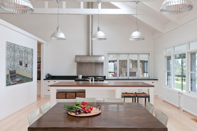 Inspiration for a contemporary eat-in kitchen in Melbourne with white cabinets and light hardwood floors.