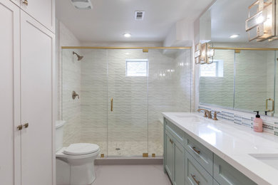 Alcove shower - mid-sized modern master beige tile and ceramic tile cement tile floor, gray floor and double-sink alcove shower idea in Houston with shaker cabinets, green cabinets, a two-piece toilet, white walls, an undermount sink, solid surface countertops, a hinged shower door, white countertops and a built-in vanity