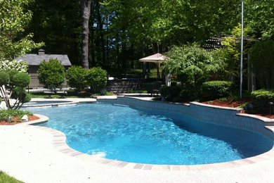 Photo of a mid-sized traditional backyard custom-shaped pool in Boston with a hot tub and concrete slab.