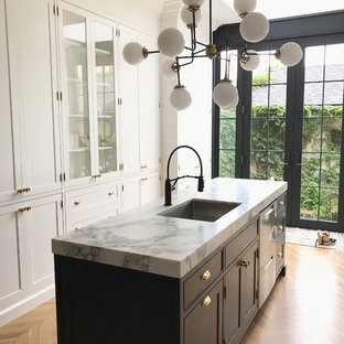 Victorian galley kitchen pantry in Toronto with an undermount sink, recessed-panel cabinets, white cabinets, marble benchtops, white splashback, porcelain splashback, stainless steel appliances, light hardwood floors, with island and white benchtop.