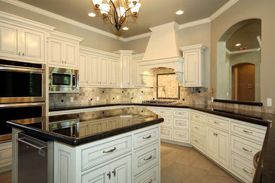 Example of a minimalist u-shaped kitchen design in Other with an undermount sink, beaded inset cabinets, distressed cabinets, granite countertops, multicolored backsplash, stone tile backsplash and stainless steel appliances