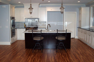 Inspiration for a mid-sized contemporary u-shaped medium tone wood floor eat-in kitchen remodel in Minneapolis with a double-bowl sink, recessed-panel cabinets, white cabinets, metallic backsplash, metal backsplash, stainless steel appliances, an island and solid surface countertops