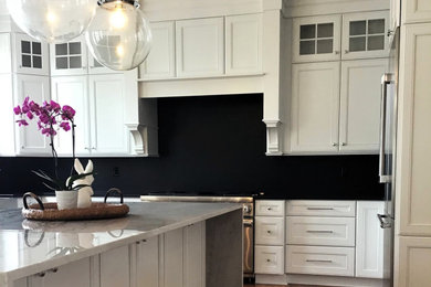 Inspiration for a large u-shaped medium tone wood floor and brown floor eat-in kitchen remodel in Other with a farmhouse sink, flat-panel cabinets, white cabinets, granite countertops, black backsplash, granite backsplash, stainless steel appliances, an island and multicolored countertops