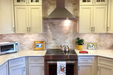 Transitional light wood floor kitchen photo in Boston with recessed-panel cabinets, beige cabinets, marble countertops, beige backsplash, stone tile backsplash and stainless steel appliances