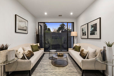 Small contemporary open concept living room in Melbourne with white walls and grey floor.