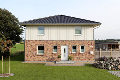 Large contemporary two-storey beige house exterior with mixed siding, a clipped gable roof and a tile roof.