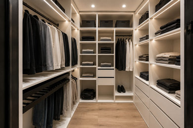 Photo of a medium sized contemporary walk-in wardrobe in Oxfordshire with flat-panel cabinets, white cabinets, light hardwood flooring, brown floors, a drop ceiling and feature lighting.