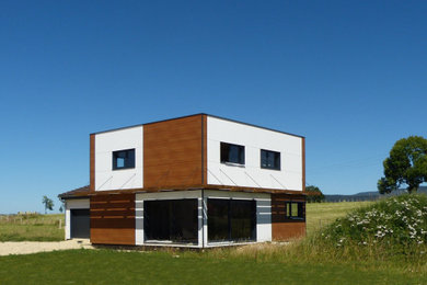 Idée de décoration pour une façade de maison blanche design en bois et planches et couvre-joints de taille moyenne et à un étage avec un toit plat, un toit végétal et un toit marron.