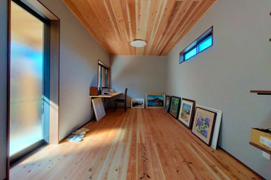 Modelo de despacho beige pequeño con paredes grises, suelo de madera clara, escritorio empotrado, suelo beige, madera y papel pintado